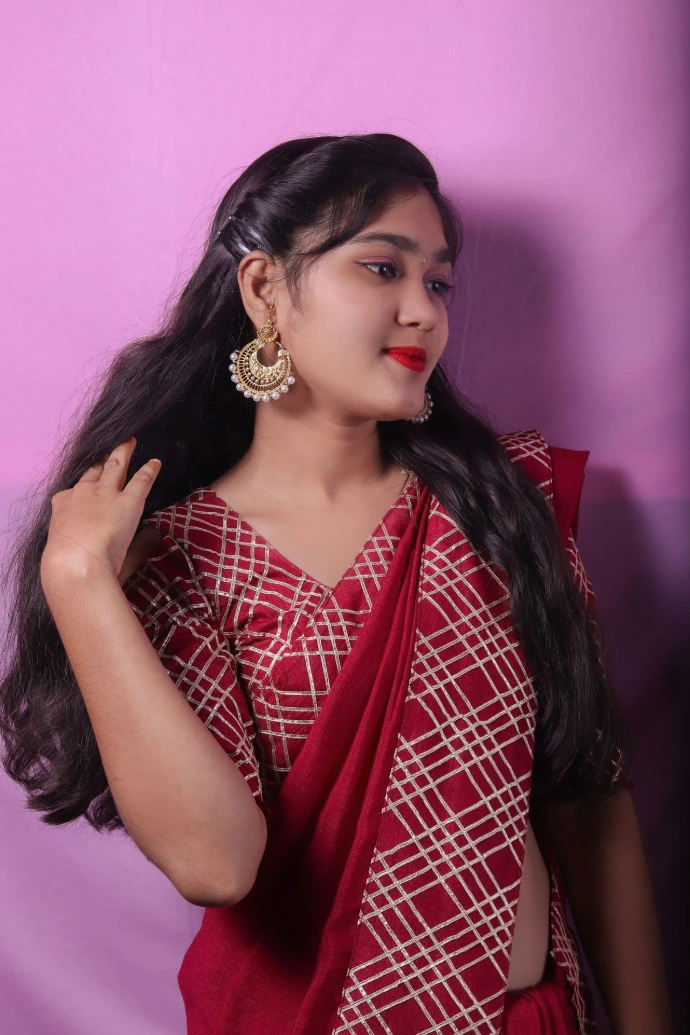 a woman wearing a red sari and gold earrings